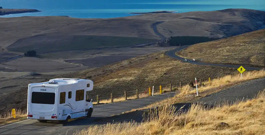 Wei&szlig;es Wohnmobil auf einer Stra&szlig;e am Tekapo-See am Mount John in Neuseeland